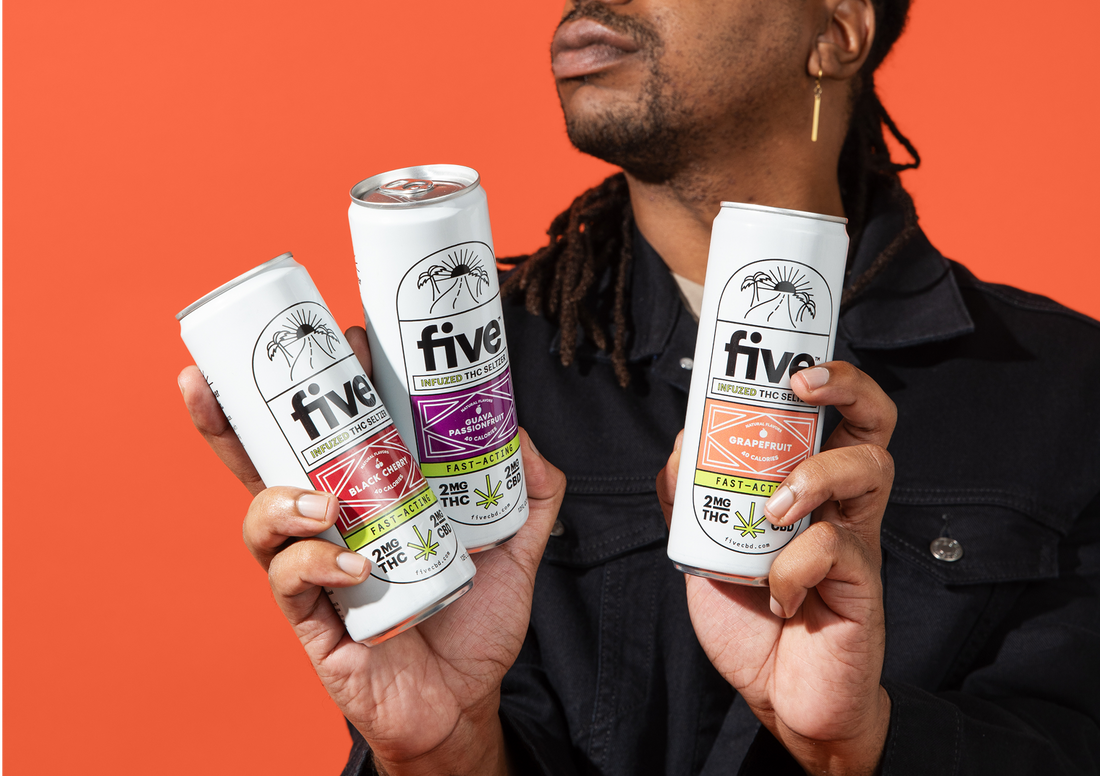 Person holding three Five THC Seltzer cans labeled Black Cherry, Guava Passionfruit, and Grapefruit, each with 2MG THC and 2MG CBD, against an orange background.