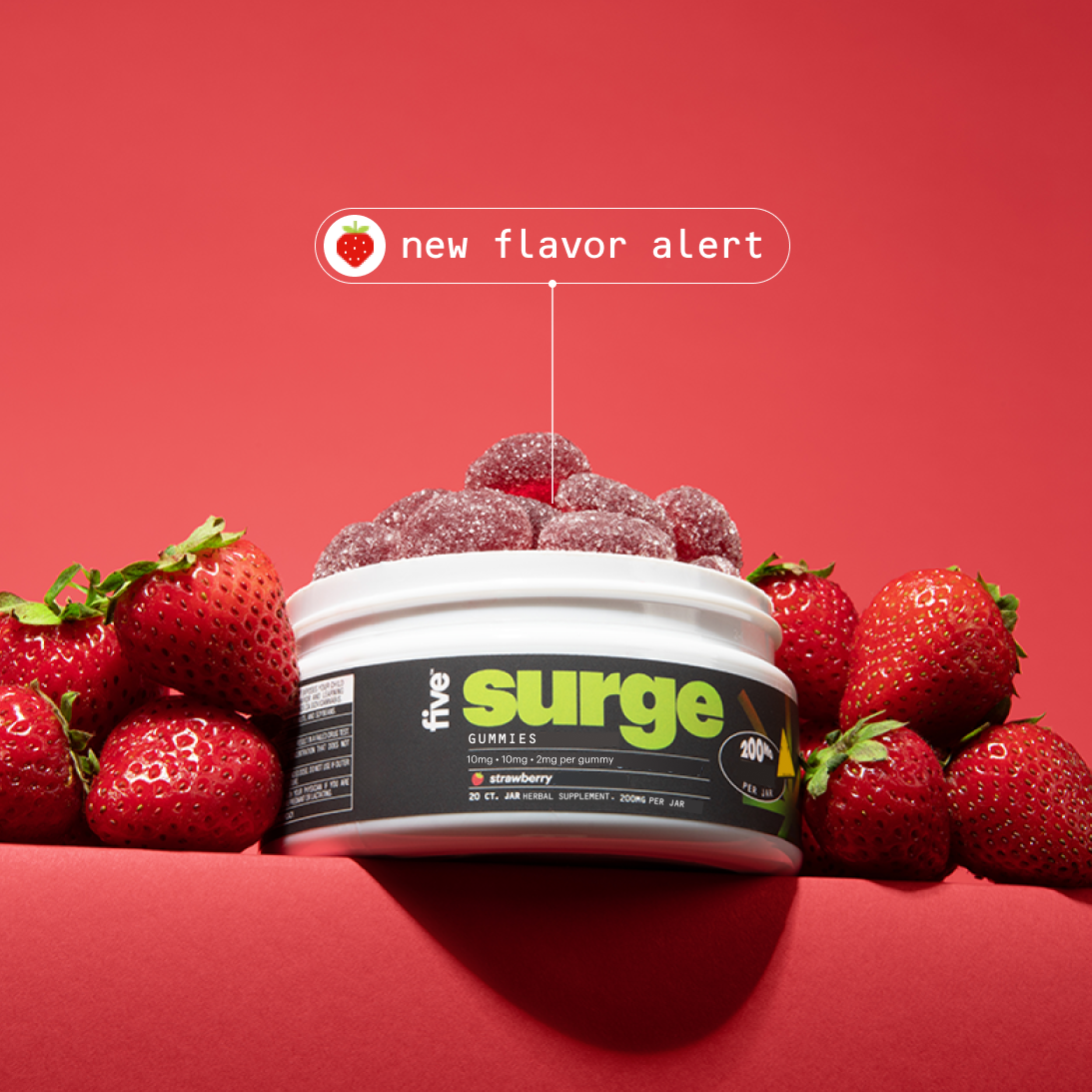 Tub of Five Surge GUMMIES (strawberry) with sugar-coated gummies and fresh strawberries; label shows "new flavor alert".