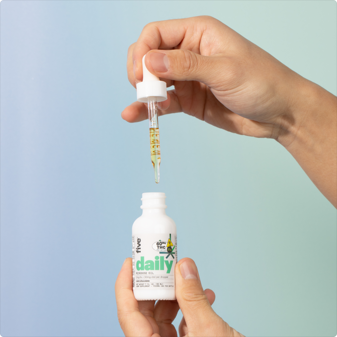Hands holding a dropper above a white tincture bottle labeled 'daily' with a small cannabis leaf