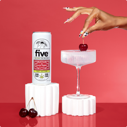 five INFUSED THC SELTZER BLACK CHERRY FAST-ACTING 2MG THC 2MG CBD can; hand with painted nails lowering cherry into glass