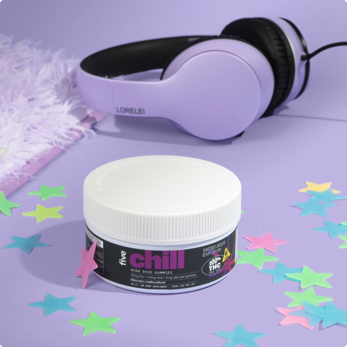 Jar labeled 'five chill HIGH DOSE GUMMIES 200MG THC' beside purple LORELEI headphones with pastel star confetti