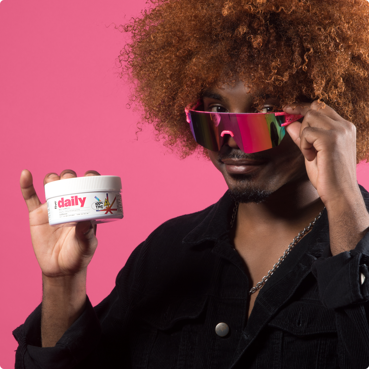 Black man adjusting pink mirrored sunglasses while holding jar labeled daily and 100mg THC.
