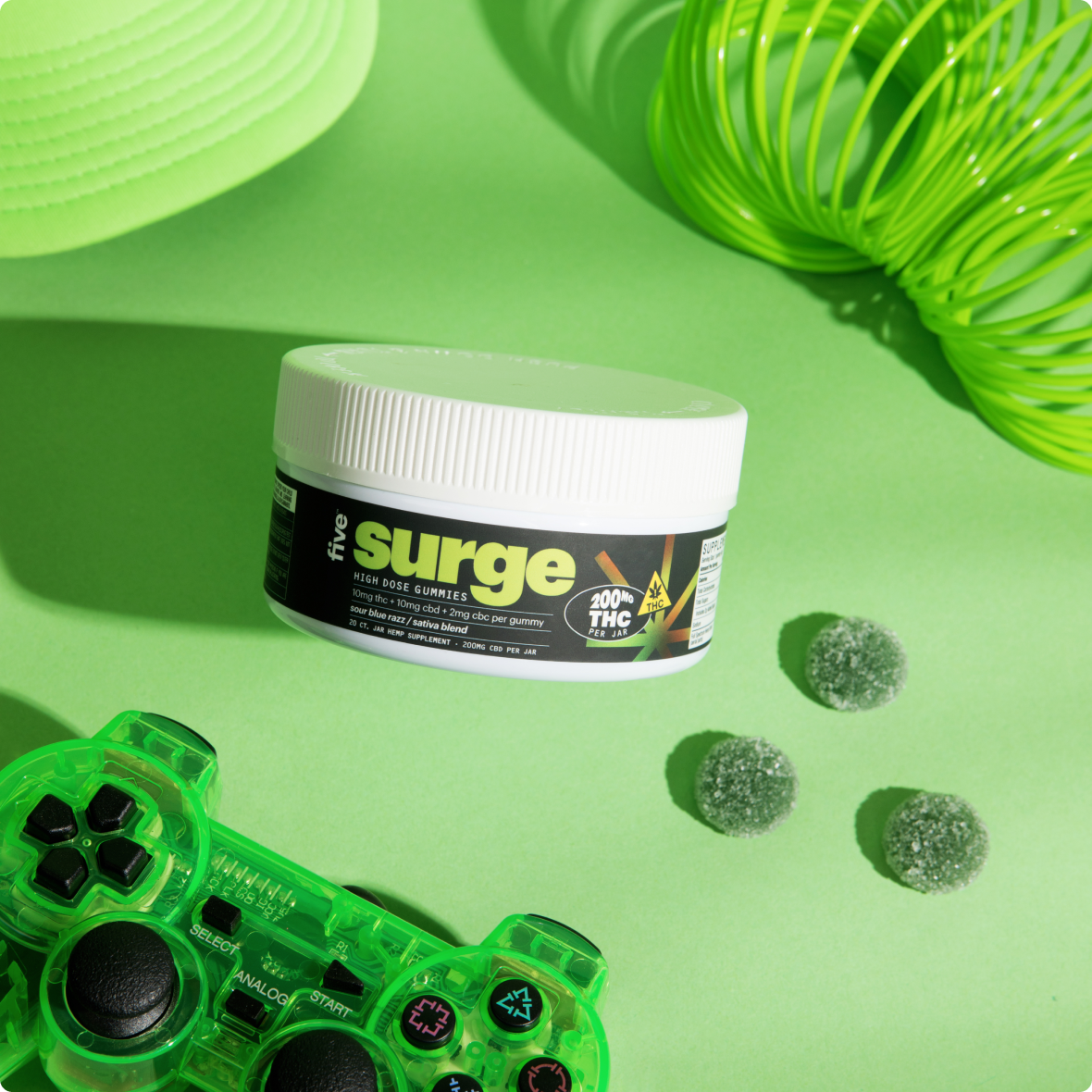 Jar labeled 'five surge HIGH DOSE GUMMIES 200MG THC PER JAR THC'; green game controller with SELECT ANALOG START buttons